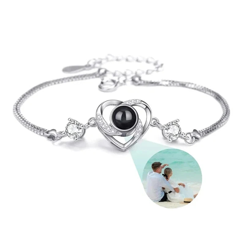 Silver bracelet with heart-shaped charm and black gemstone on a white background