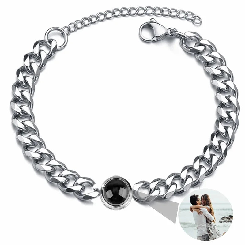 Silver chain bracelet with a black heart charm on a white background