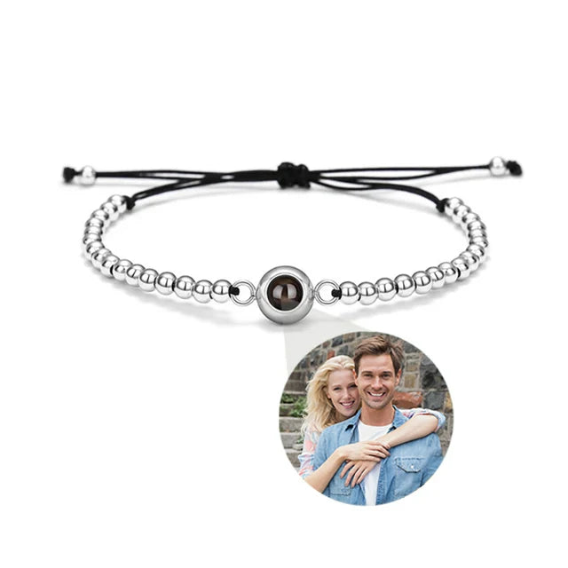 Silver beaded bracelet with a black cord, featuring a photo of a couple on a white background.