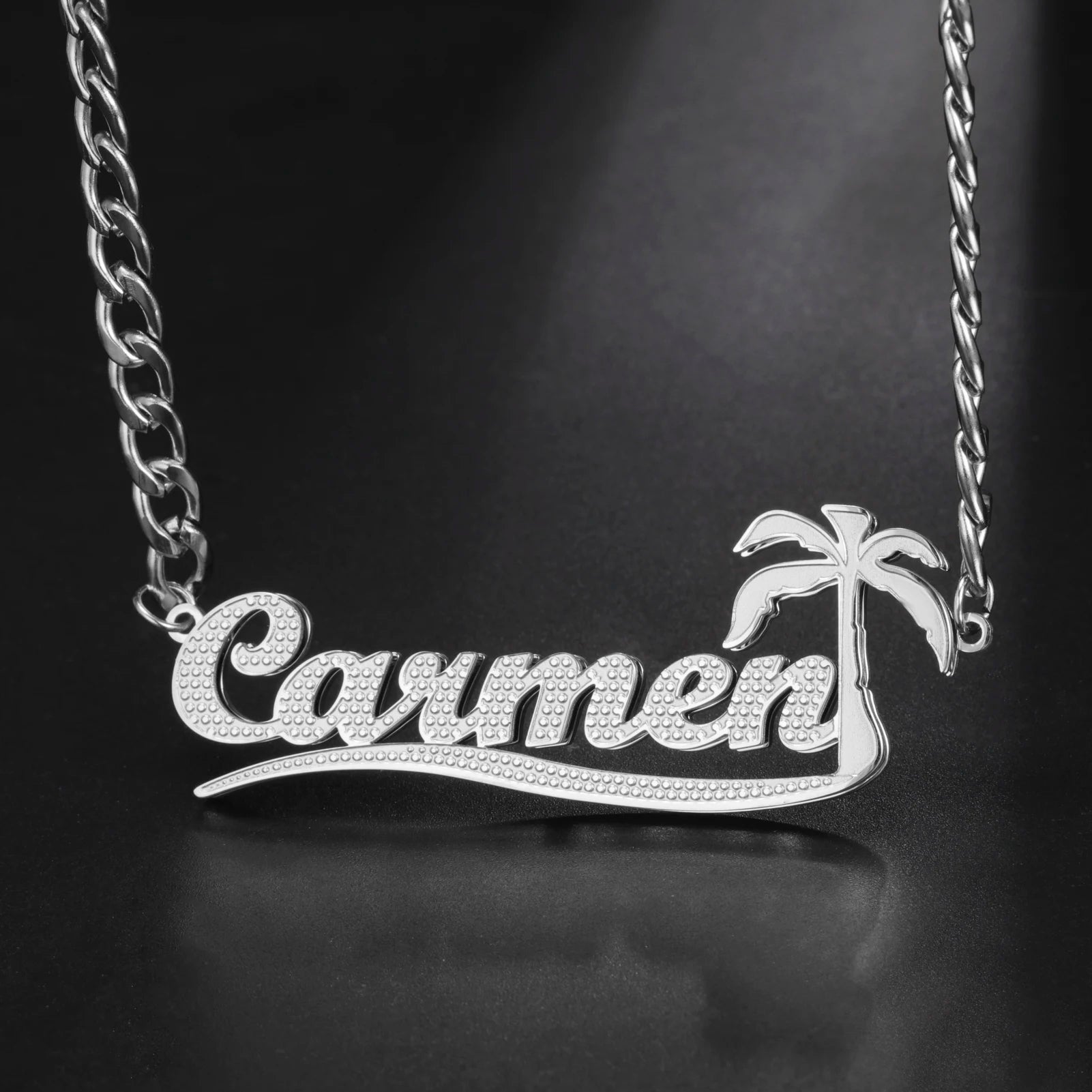 Silver necklace with 'Carmen' and palm tree design on a dark background