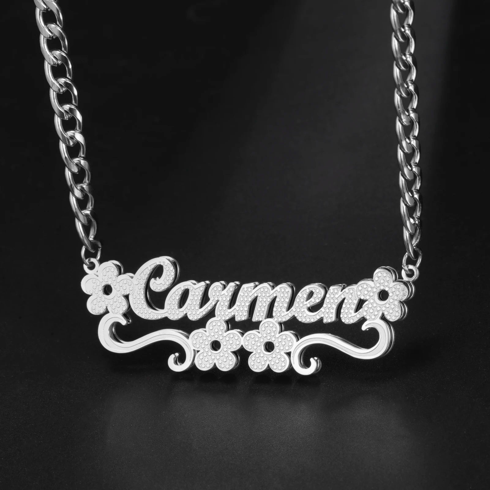 Silver necklace with 'Carmen' pendant on a black background