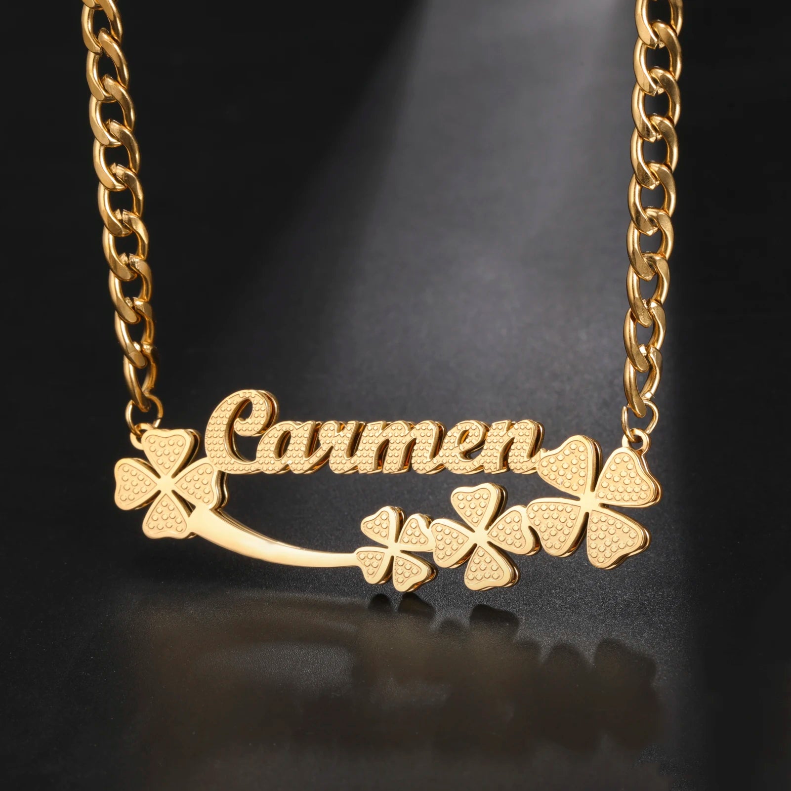 Gold necklace with 'Carmen' and clover designs on a dark background