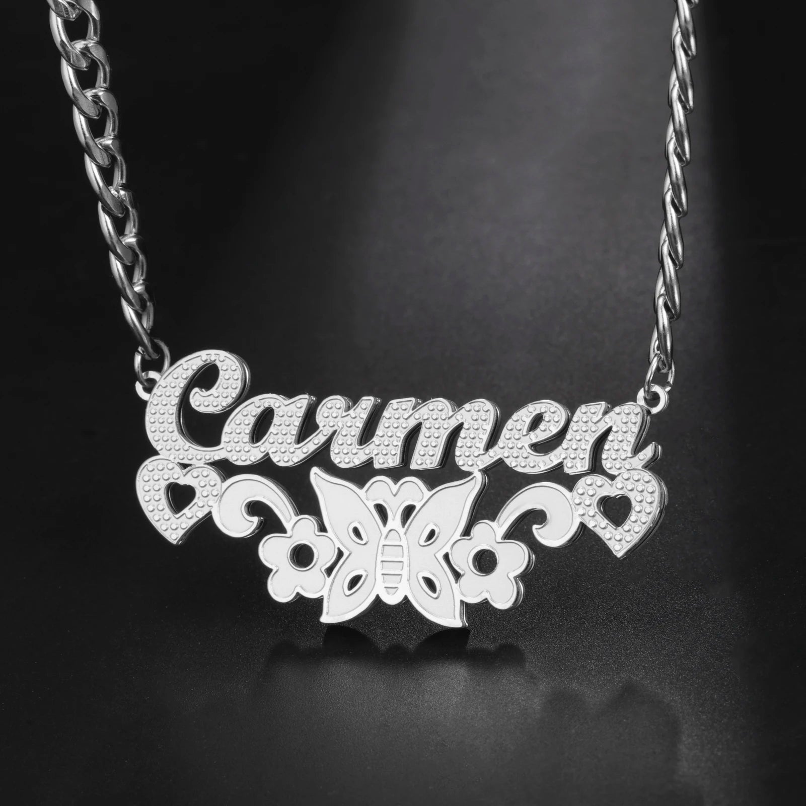 Silver necklace with 'Carmen' and butterfly design on a dark background