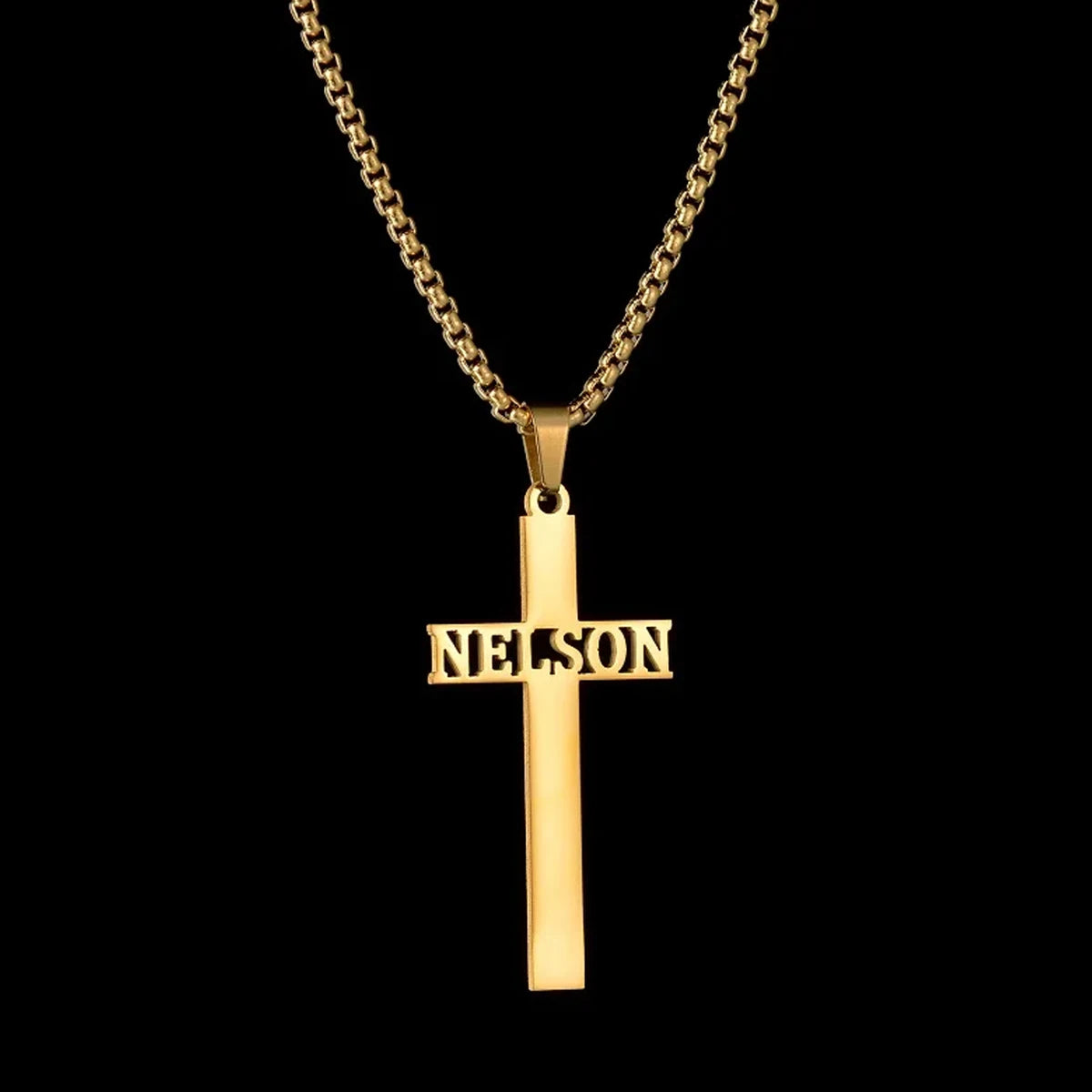 Gold cross pendant with 'NELSON' engraving on a black background