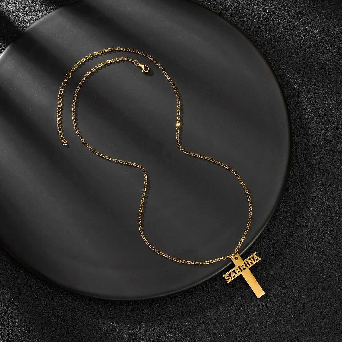 Gold necklace with a cross pendant on a black plate