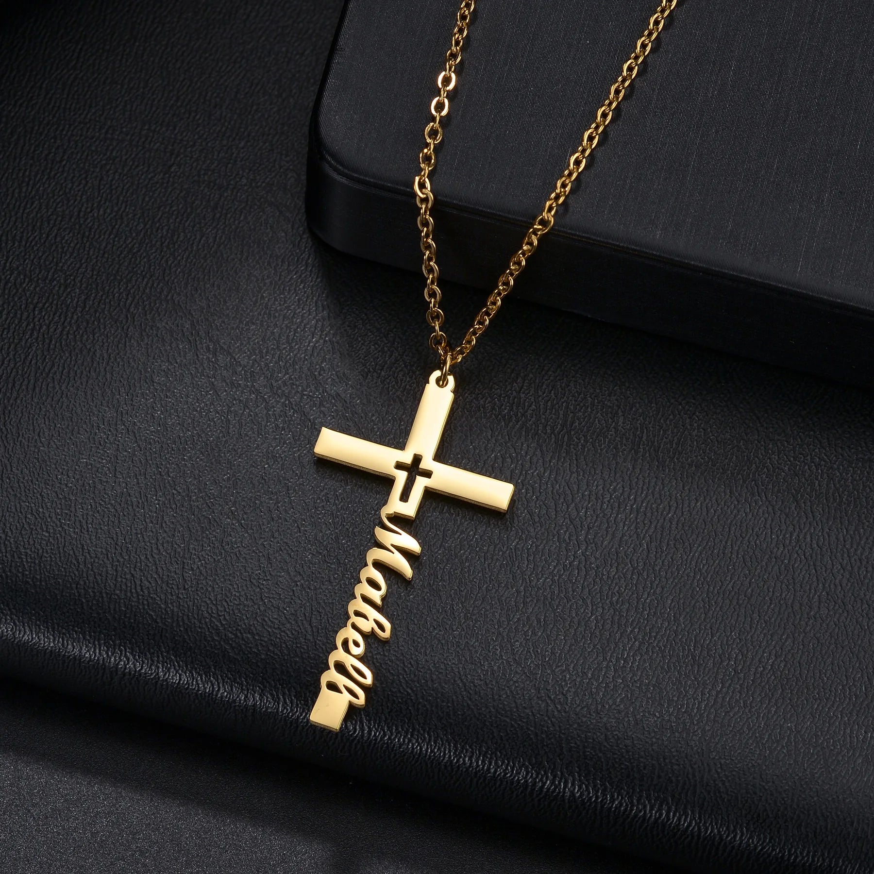 Gold cross necklace with 'love' engraving on a black surface