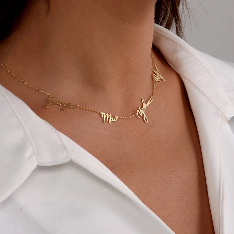 Gold necklace with name charms on a person wearing a white shirt.