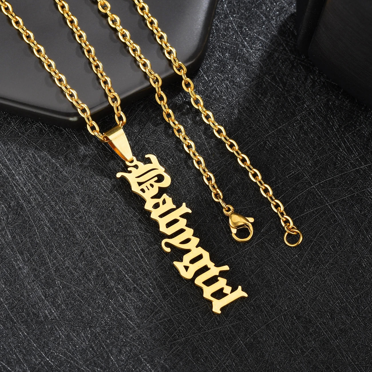 Gold necklace with a pendant on a black textured background