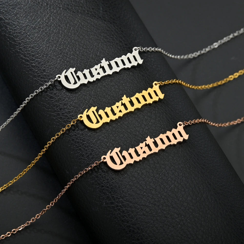 Four customizable namechains in silver, gold, rose gold, and bronze on a dark textured surface.
