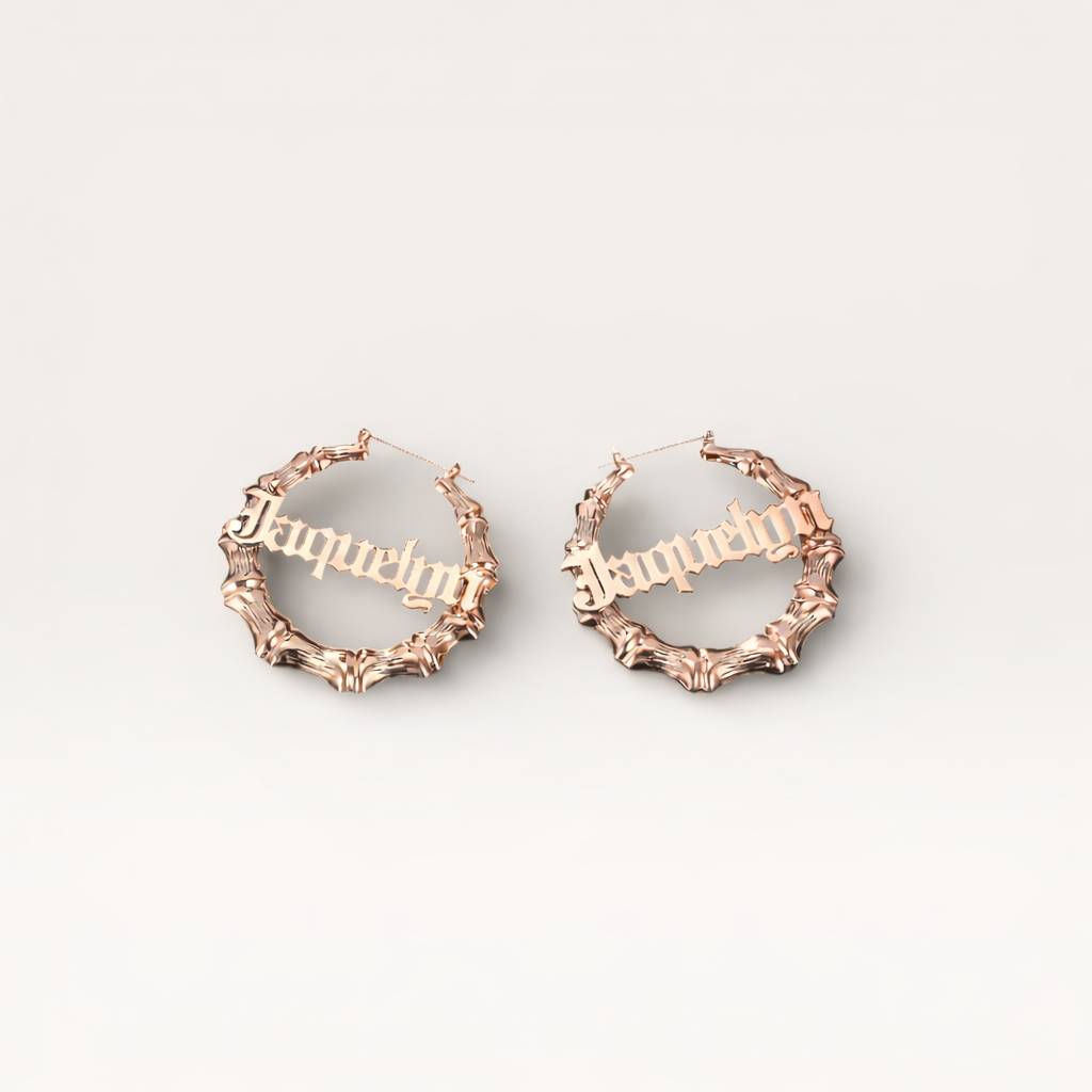 Rose gold hoop earrings with 'Jacqueline' engraving on a light gray background