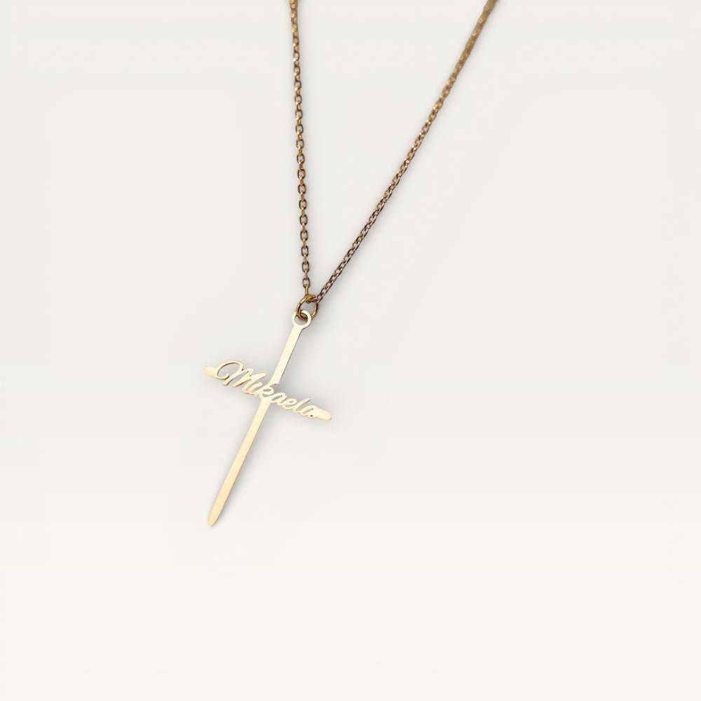 Gold necklace with a cross pendant on a light gray background