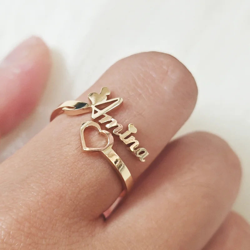 Gold ring with 'Amira' on a finger against a white background