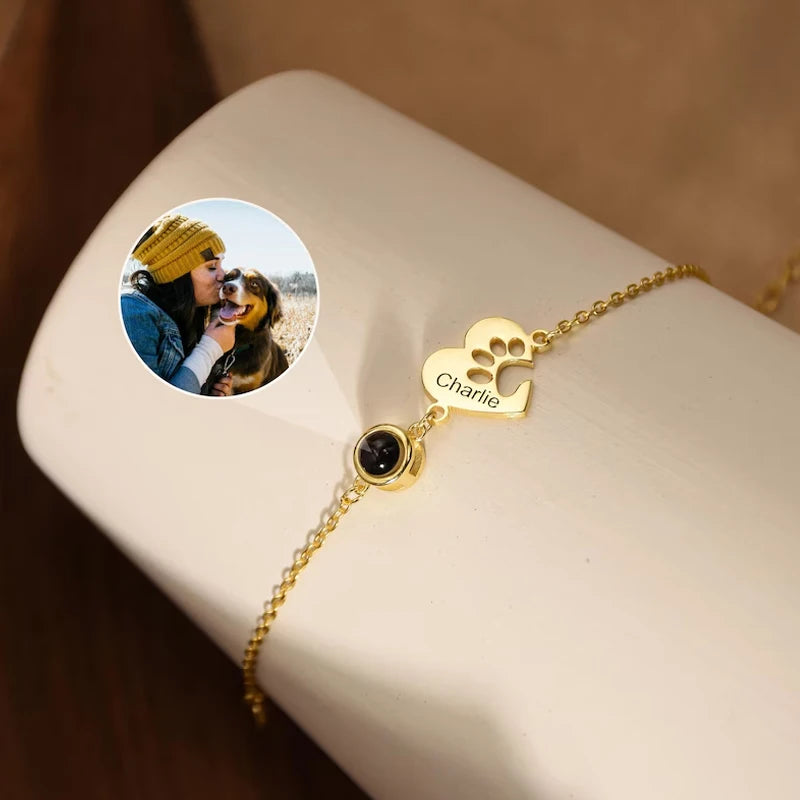 Gold bracelet with paw-shaped charm and 'Charlie' engraving on a white surface.