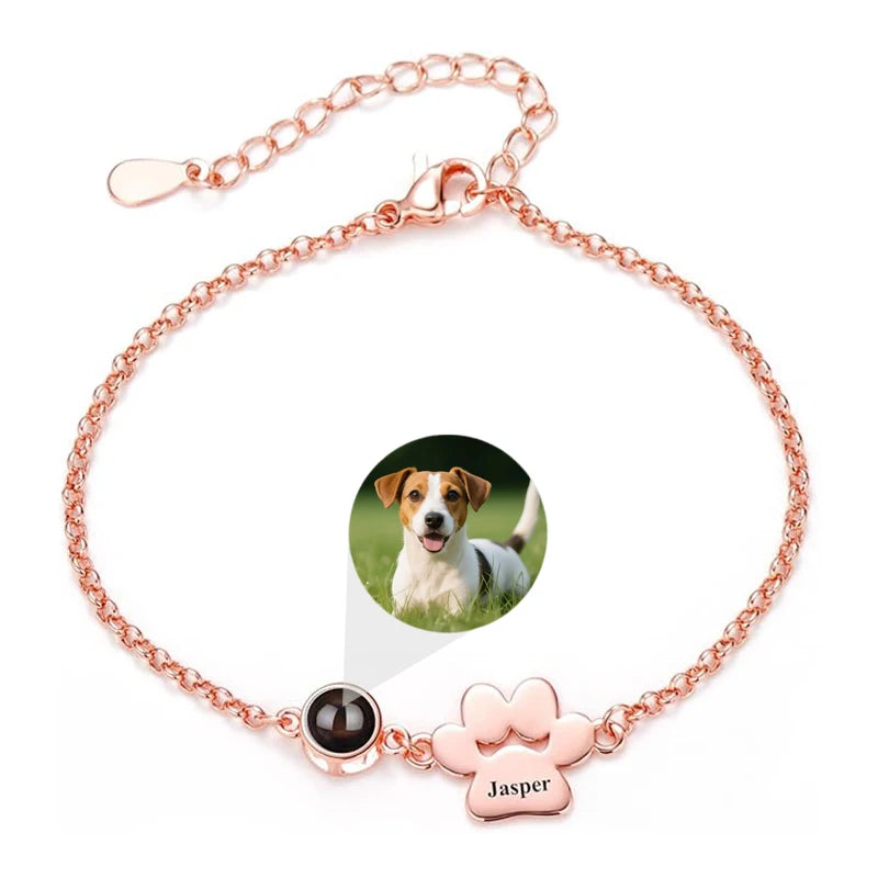 Rose gold bracelet with paw charm and photo of a dog on a white background