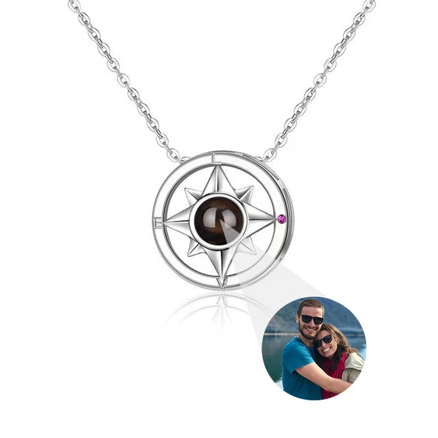 Silver compass necklace with a small circular inset photo of a couple on a white background