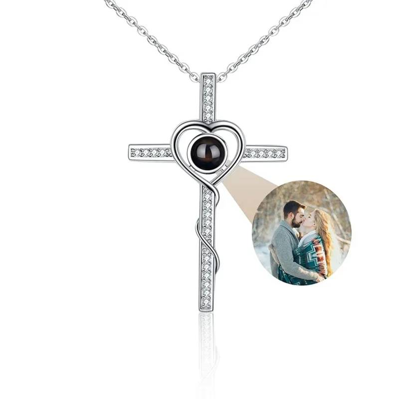 Silver cross necklace with heart-shaped photo insert on a white background