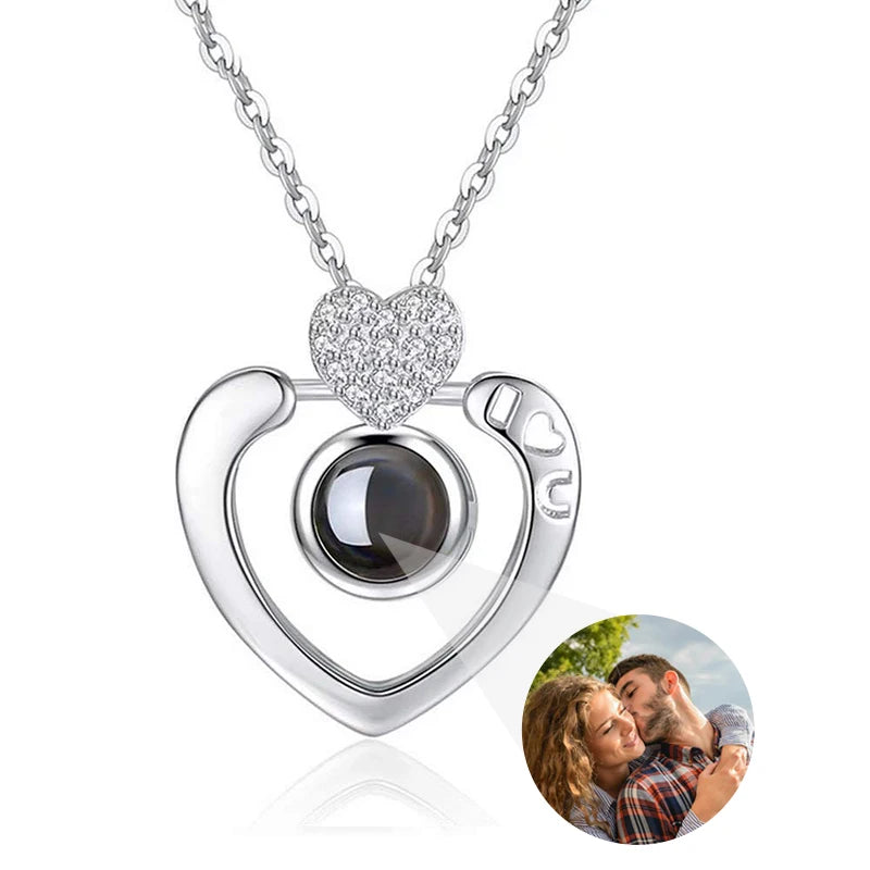 Heart-shaped silver pendant with a black stone on a white background