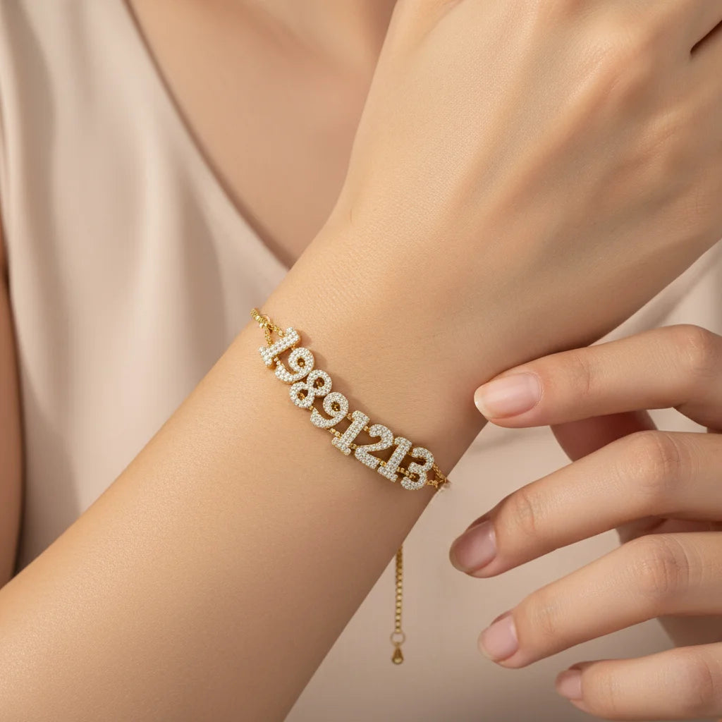 Gold bracelet with numbers on a wrist against a neutral background