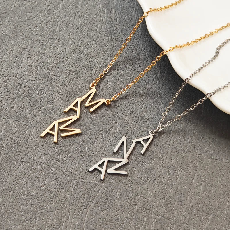 Two necklaces with geometric pendants on a textured gray surface